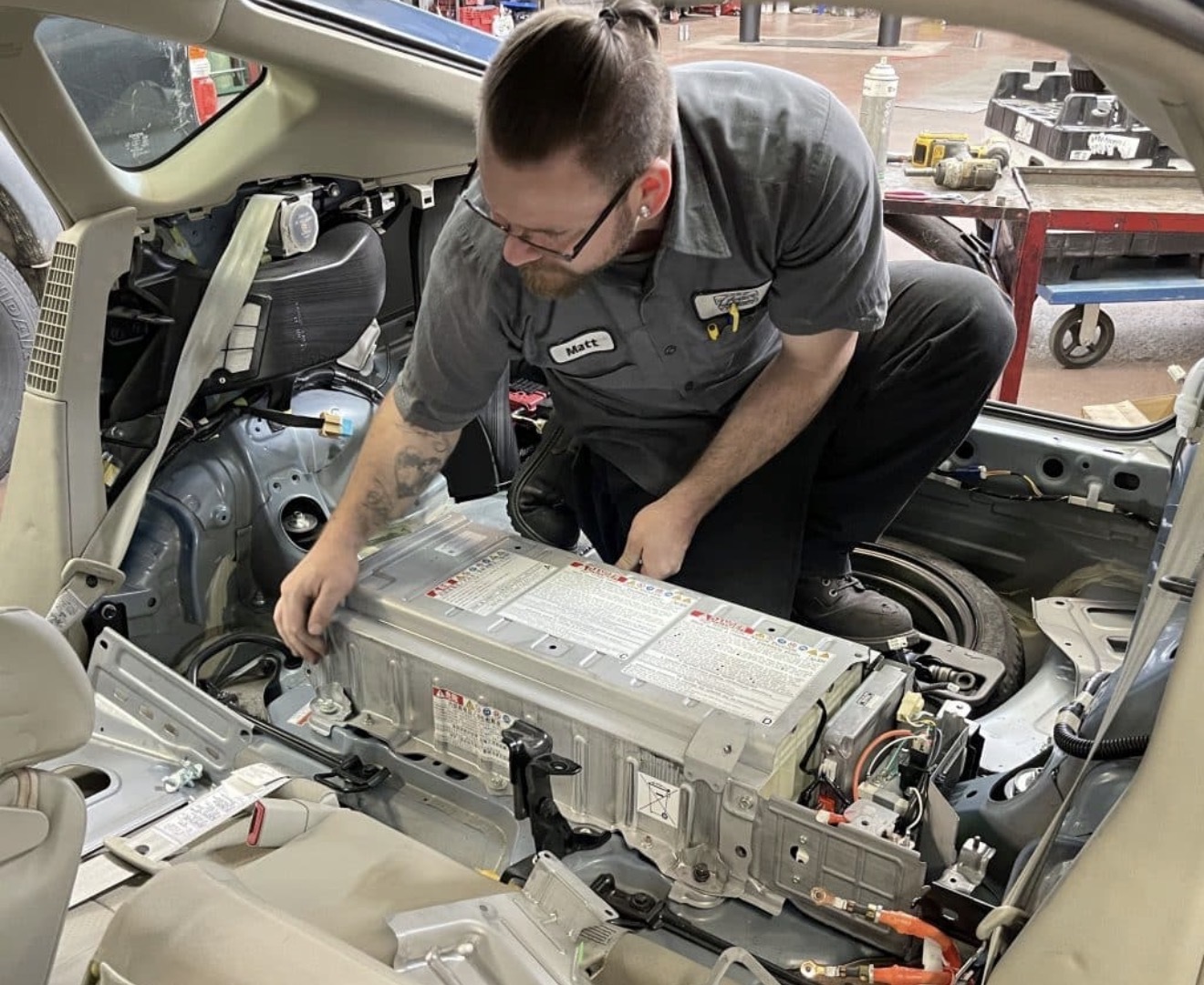 Battery Repair Experts technician installing a replacement hybrid battery pack inside a vehicle