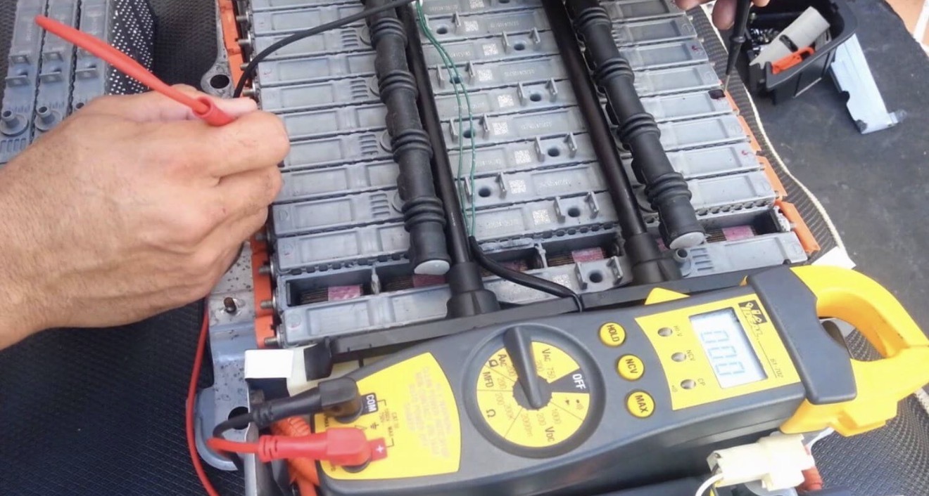Individual hybrid battery modules being tested with a multimeter during cell revitalization